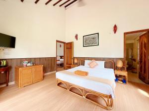a bedroom with a large bed and a television at Little Muine Cottages Resort in Mui Ne
