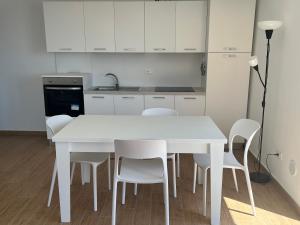 a white kitchen with a white table and chairs at Casa Ludovica in Gioiosa Marea