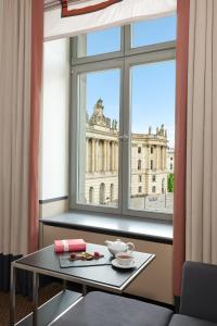 a table in front of a window with a view of a building at Rocco Forte Hotel De Rome in Berlin