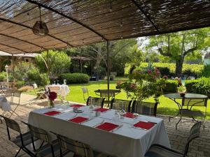 a table under a pergola with tables and chairs at Logis Hôtel Restaurant La Sommellerie in Châteauneuf-du-Pape