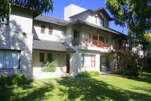 una gran casa blanca con un patio verde en Maritimo Apart en Pinamar