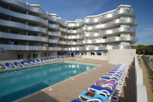 un hôtel avec une piscine et des chaises longues dans l'établissement Résidence Odalys Le Lotus Blanc, au Barcarès