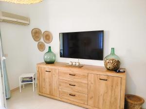 a television on top of a wooden dresser with two vases at Milion Destiny Entre Playas in Oropesa del Mar