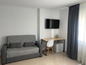 a bedroom with a bed and a desk with a television at Albergue San Pedro in Corcubión