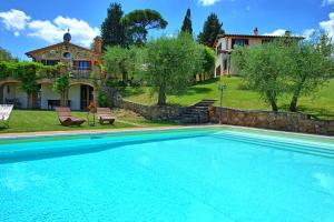 a large swimming pool in front of a house at Villa Ulivi by PosarelliVillas in Lucignano