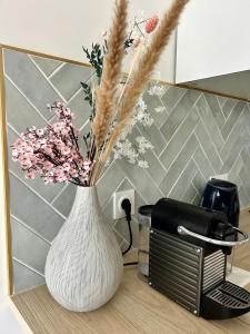 un vase blanc avec des fleurs sur un comptoir à côté d'un grille-pain dans l'établissement Élégant Appartement Minimaliste entre Paris et Disney, à Noisy-le-Grand