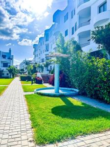 a fountain in the grass next to a building at Superbe appartement vue sur mer in Marina Smir