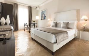 sypialnia z dużym białym łóżkiem i krzesłem w obiekcie Hotel Vittoria w mieście Faenza +37 zdjęć