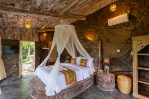 ein Schlafzimmer mit einem Bett in einem Steinzimmer in der Unterkunft Royal Kemala Villa - Jungle View with Private Pool in Tampaksiring
