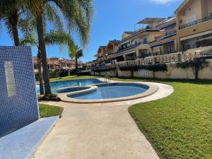 a swimming pool in front of a building with palm trees at Lux de Novamar en Gran Alacant in Puerto Marino