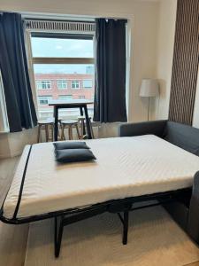 a bed in a room with a table and a window at Cosy Apartment in the Hague! in The Hague