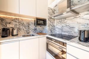 una cocina con armarios blancos y encimeras de mármol en GuestReady - Áurea Art apartment, en Lisboa