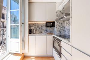 Una cocina con gabinetes blancos y una ventana. en GuestReady - Áurea Art apartment, en Lisboa