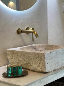 a stone sink with four bottles ofodorizers on a counter at Casa Postigo no Campo in Campinho +19 photos