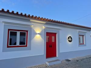 a white house with a red door and windows at Casa Postigo no Campo in Campinho