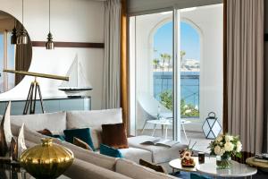 a living room with a couch and a sailboat on the window at Hôtel Barrière Le Majestic Cannes in Cannes
