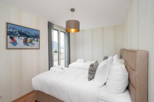 a bedroom with a large white bed and a window at Montreux Four Bedroom Penthouse by Swiss Hotel Apartments in Montreux