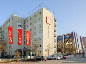 a large building with cars parked in a parking lot at ibis Stuttgart Airport Messe in Leinfelden-Echterdingen