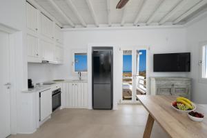 a kitchen with white cabinets and a black refrigerator at Sunrise Villa - Sea View Private Pools in Mýkonos City