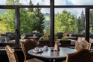 a table and chairs in a room with a large window at Wellness Hotel Šedý Vlk in Harrachov
