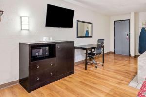 a living room with a desk and a tv on a wall at Econo Lodge Akron Copley Northwest in Montrose