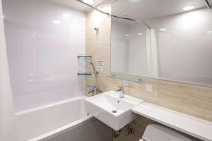 a bathroom with a sink and a tub and a mirror at Comfort Hotel Nagoya Shinkansenguchi in Nagoya