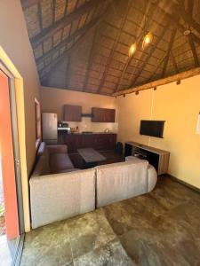 a living room with a couch and a kitchen at Falcon Lodge ET in Bela-Bela