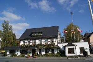 ein weißes Gebäude mit schwarzem Dach in der Unterkunft Hotel Keller in Kreuztal