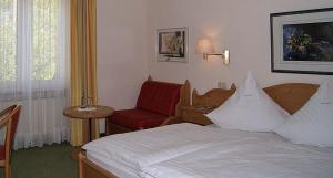 um quarto de hotel com uma cama e uma cadeira vermelha em Hotel Keller em Kreuztal