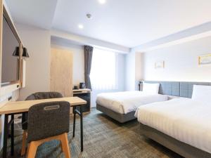 a hotel room with two beds and a desk at Comfort Hotel Nagoya Shinkansenguchi in Nagoya