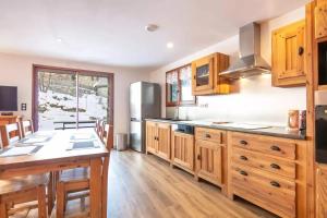 a kitchen with wooden cabinets and a refrigerator at Maison conviviale à Valloire + Jardin in Valloire