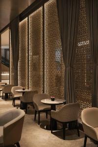 Kempinski Central Avenue Dubai في دبي: مطعم بطاولات وكراسي وستارة