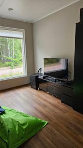 a living room with a flat screen tv and a large window at Ketunpesä 8 in Karkkila