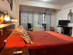 ein Schlafzimmer mit einem roten Bett, einem Tisch und Stühlen in der Unterkunft Gregorio I Hotel Boutique in San Salvador de Jujuy