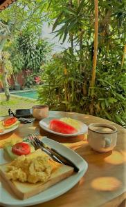 a table with a plate of breakfast food on it at Werkudara Guest House in Ubud