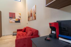 a living room with a red couch and a tv at Le Stanze di Gianmarmo - Galleria 41037 in Mirandola