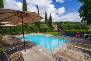basen z krzesłami i parasolem w obiekcie Agriturismo Fattoria Podere Peciano w mieście Cortona