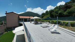a patio with white lounge chairs and an umbrella at vignale holiday house in La Spezia