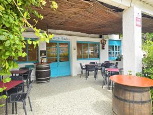 a restaurant with blue doors and tables and chairs at Camping Costa Dorada Bungalow Maia in Canet de Mar