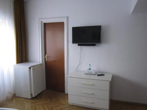 a bedroom with a dresser and a tv on the wall at Pensiunea Helvetia in Bucharest