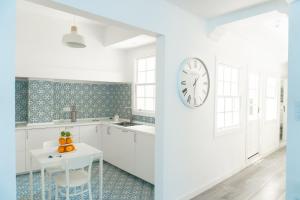 a kitchen with white cabinets and a clock on the wall at The Sea Corner Vacacional La Palma in Santa Cruz de la Palma +35 photos