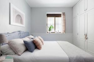 a white bedroom with a bed with pillows and a window at Acogedor apartamento en Santa Fe in Santa Fe
