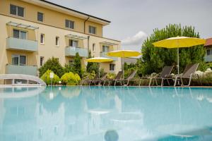 巴特拉德克斯堡的住宿－Hotel Garni Toscanina - Adults Only，一座带椅子和遮阳伞的游泳池位于一座建筑旁边