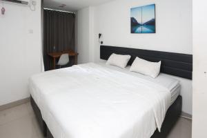a bedroom with a large bed with white sheets at RedLiving Apartemen Enviro Cikarang - Stars Rooms in Cibeber +24 photos