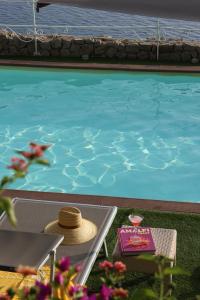 a hat sitting on a table next to a swimming pool at Hotel Piccolo Sant'Andrea in Praiano