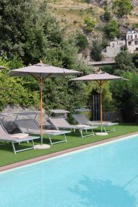 a group of chairs and umbrellas next to a pool at Hotel Piccolo Sant'Andrea in Praiano