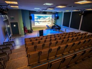 un auditorium vide avec une scène et un piano à queue dans l'établissement Lofoten sommerhotell og vandrerhjem, à Kabelvåg