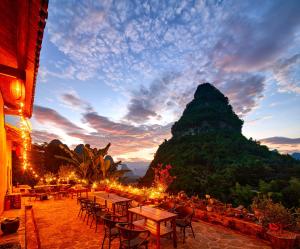 a restaurant with tables and chairs and a mountain at Yangshuo Yunshe Mountain Guesthouse in Yangshuo