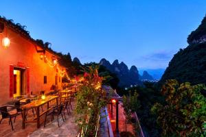 a restaurant with tables and chairs on a balcony at Yangshuo Yunshe Mountain Guesthouse in Yangshuo