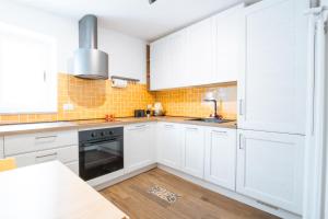 a white kitchen with white cabinets and a wooden floor at La Pinta in Mola di Bari